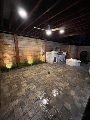 Pavers, outdoor kitchen, cedar pergola, custom lighting, landscaping, water feature, and stone fire pit.