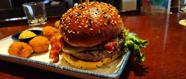 Bacon Cheeseburger: Grilled patty topped with bacon, cheddar, lettuce, tomato & our signature sauce. Served on a sesame bun with 1 side.