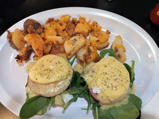 Eggs Benedict with fresh tomatoes and spinach added and well done cheese covered home fries.