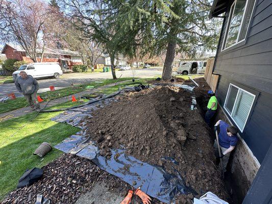 Excavated dirt on protective sheets laid over the lawn