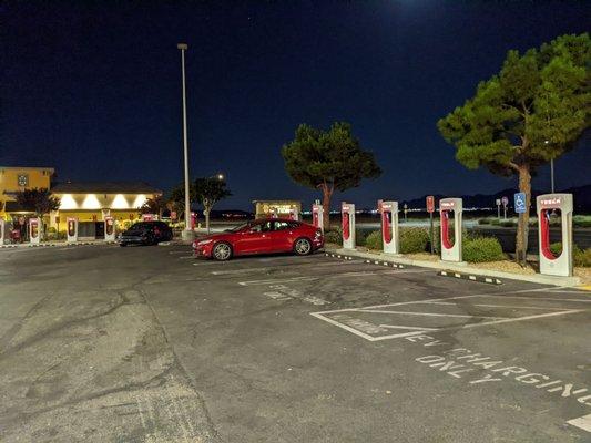 Sexy red Tesla next to superchargers