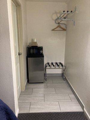 Small fridge w/microwave on top. Open closet concept and entryway to bathroom.