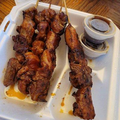 BBQ pork skewers with spicy dip of soy sauce, vinegar, garlic, onions and peppers