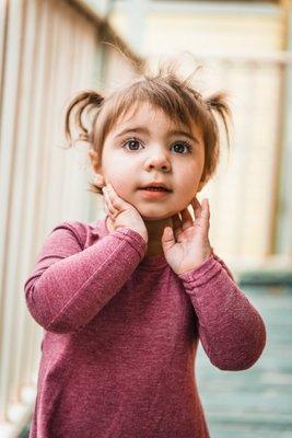 Young girl in pigtails looks up curiously at her mother.