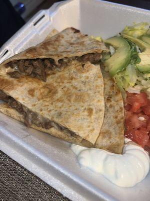 Fajita quesadilla with lettuce, avocado slices, tomatoes and sour cream