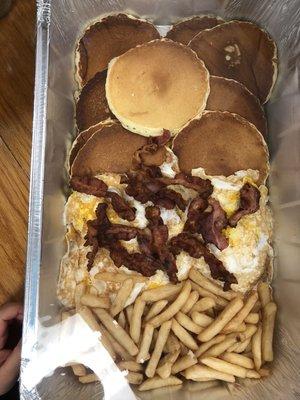 A family breakfast tray. 10 pancakes, 10 scrambled eggs, 10 pieces of bacon and French fries or home fries.