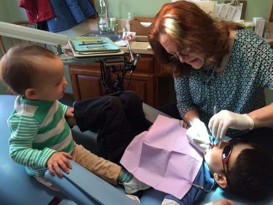 Kiddo getting his teeth cleaned as sister looks on