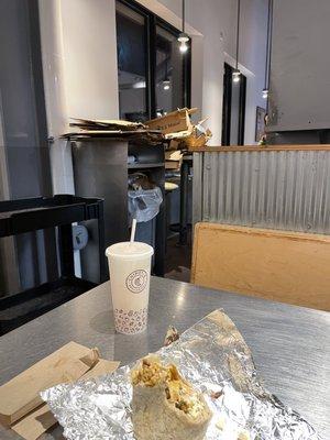 cardboard stacked on table where people eat over flowing garbage.