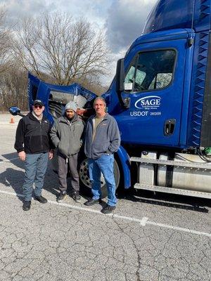 Sage faculty and students posing in front of training vehicle.