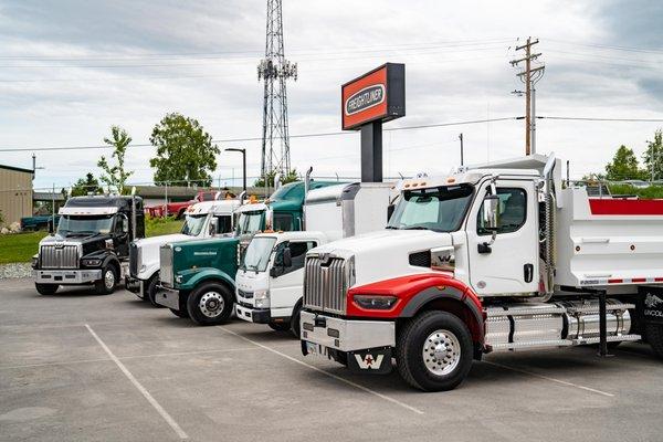 A lineup of heavy duty vehicles at TrailerCraft, including Weatern Star and Freightliner trucks.