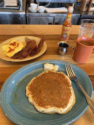 Pancakes, soft scrambled eggs, bacon, and coffee.