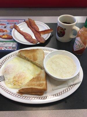 Eggs over medium, baco, grits, and coffee.