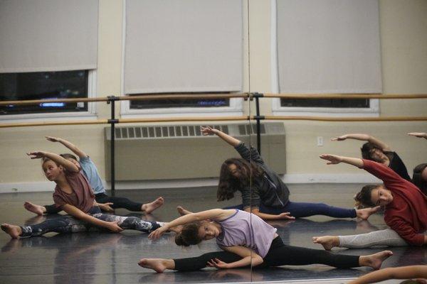 Youth dancers stretch during warm ups