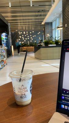 Iced caramel macchiato + main view in front of the shop