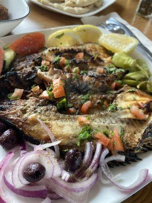 Masakuf whole Tilapia fish grilled in the Iraqi way served with lemon tomato and bread