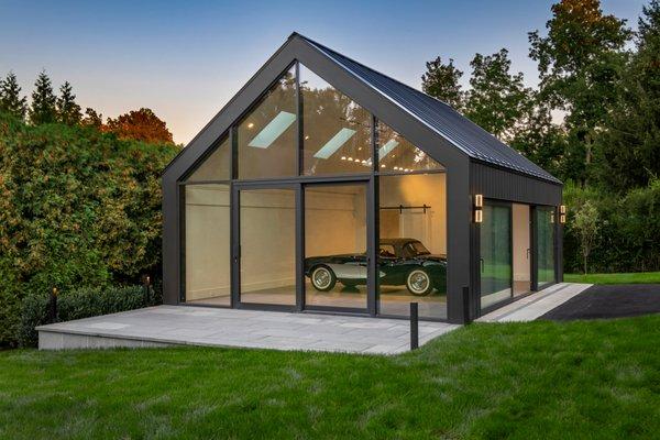 Car in a modern barn structure at sunset.