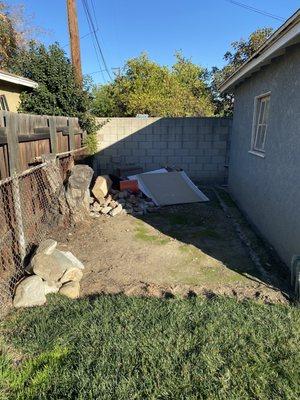 Before- broken concrete, bricks, building material, and tree stump.