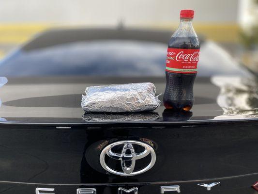 A picture of the burrito and a Coca-Cola sitting on the trunk of the car to give you an idea of the size.