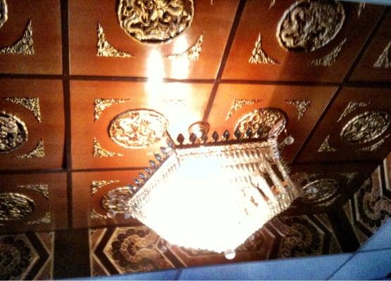 The ceiling features these cool unset wooden/golden tiles and a chandelier.