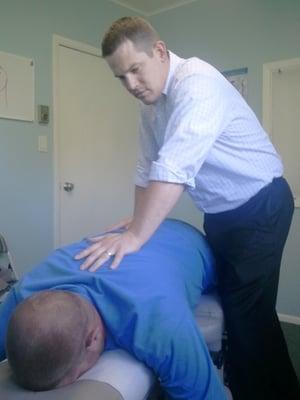 Dr. Brock Mattson, D.C. checks a patients' spine for spinal misalignment(s).