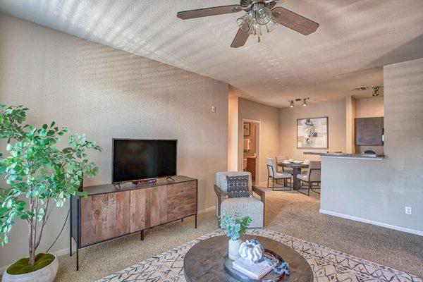 a living room with a ceiling fan and a tv at Spring Creek Apartments