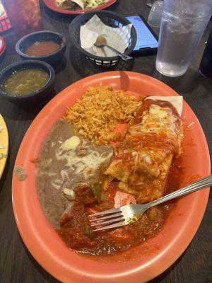 Smothered red pork burrito with a side of rice and bean