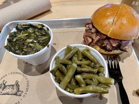 Brisket sandwich on a potato bun with collard greens and green beans