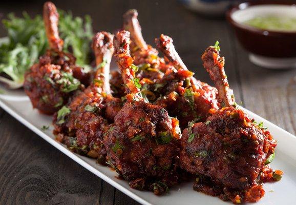 Crispy, spicy chicken wings shaped like lollipops, served with a tangy dip.