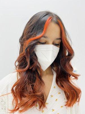 A red balayage is a hair color that involves a freehand painting technique to dye the hair with red hues to create highlights or ombres.