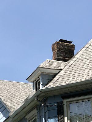 Waterproofing chimney top of roof shingle house.