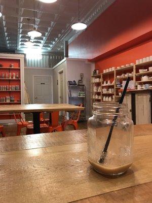 Back room with pottery and glazes on the walls. Empty iced chai for scale.