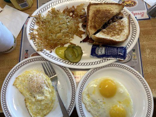 Hash brown, pickles, Texas bacon cheesesteak one over easy egg, two Sunnyside up eggs