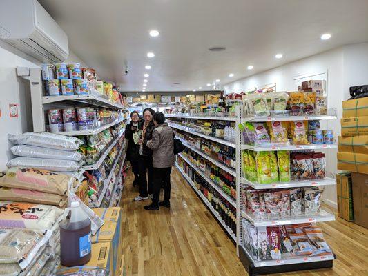 Two aisles of dry food with a refrigerated and frozen section in back.