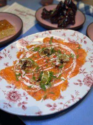 Smoked salmon carpaccio with yu choy, charred lime, coconut chili crisp sauce, baby cilantro, crushed toasted peanuts