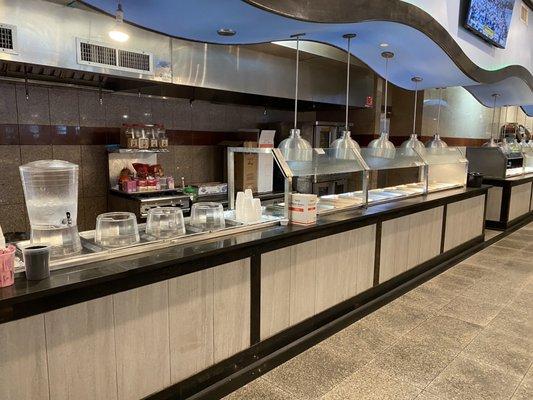 Spices and boxes being stored on cooktops. Self serve water and unused buffet area.