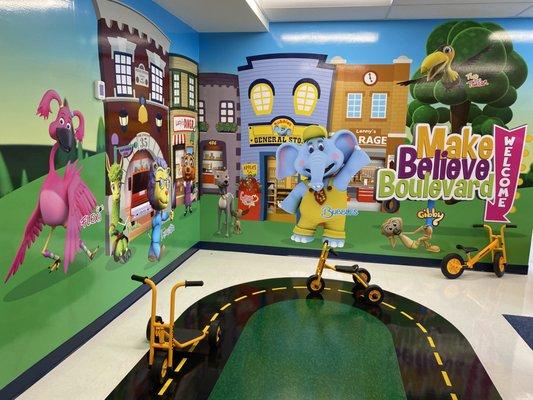 Indoor playground with bikes, scooters, and colorful background