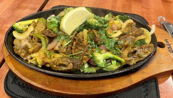 Lamb Seekh Kabab. Kabob is sliced up and comes out on a sizzling cast iron plate over delicious vegetables.  Will reorder.