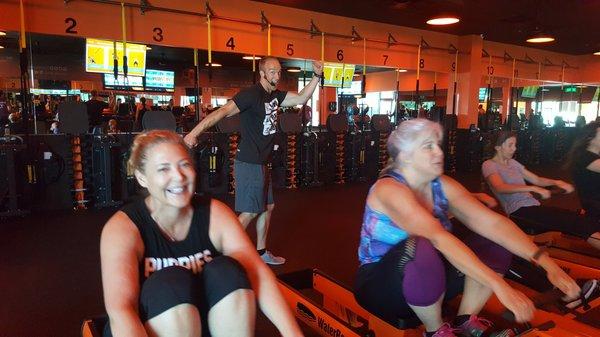 Gina and Mary B on rowers, with Coach Dave in the background.