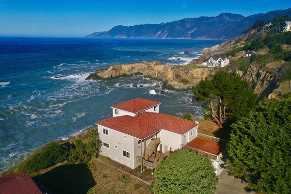 Drone view of Cliff House, a Hotel in Shelter Cove, CA. King Range Mountains and Lost Coats Trail in the background.