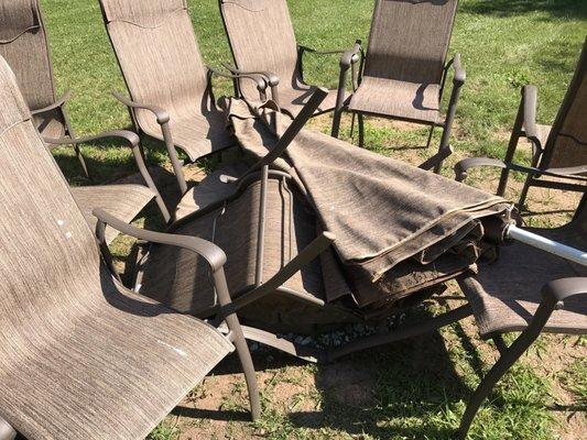 Chairs thrown together with the umbrella on top.