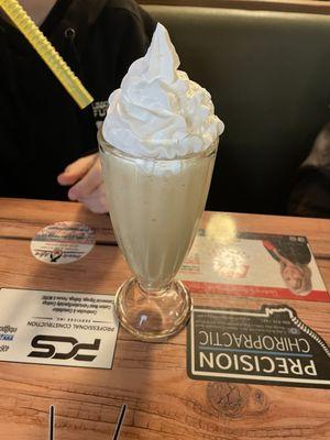 Vanilla milkshake with whip cream on top.