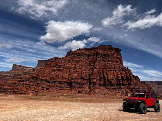 A red Jeep Wrangler rented from Twisted Jeeps driving through Canyonlands National Park.