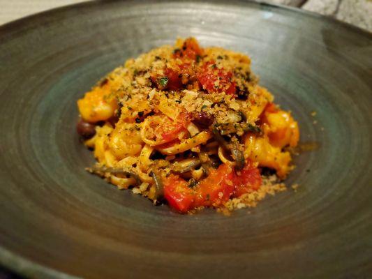 Squid ink and egg chitarra, shrimp, brandy, Taggiasche olives fresh tomatoes, chili oil, gremolata