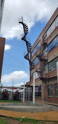 Spiral fire escape sculpture titled Architectural DNA between buildings