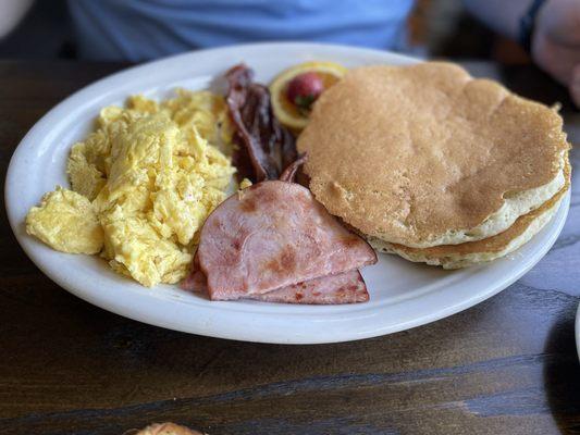 Eggs with short stack of pancakes, bacon and ham