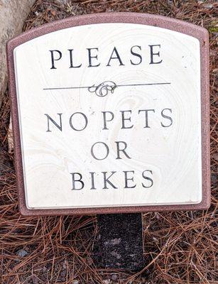 This sign is at both entrances that pets and bikes are not allowed in the garden.  Photo taken March 25, 2023.