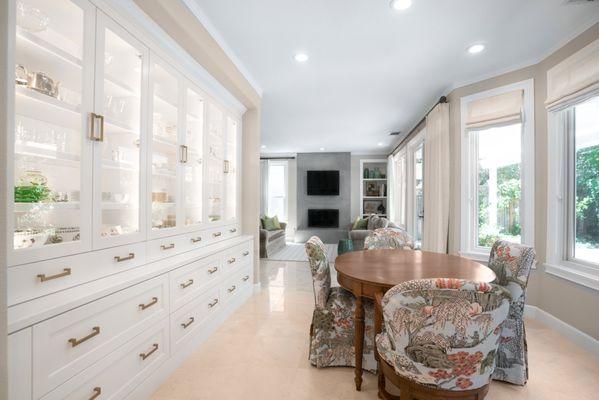 Custom cabinetry with glass-front doors elegantly showcases collectibles, adding a sophisticated touch to this light-filled dining space.