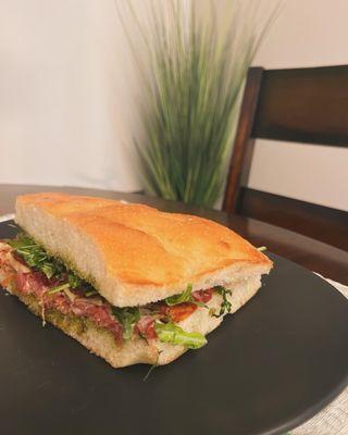 #5, the Gandolfini panino with sweet capicolla, bresaola, sharp provolone, sun-dried peppers, baby arugula, and basil pesto spread.