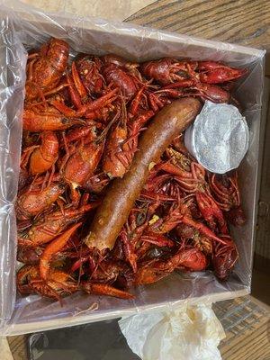 3lb box of crawfish with huge piece of sausage and side of butter