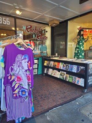 Outside entrance area has a vintage clothing rack display and table with quality used books